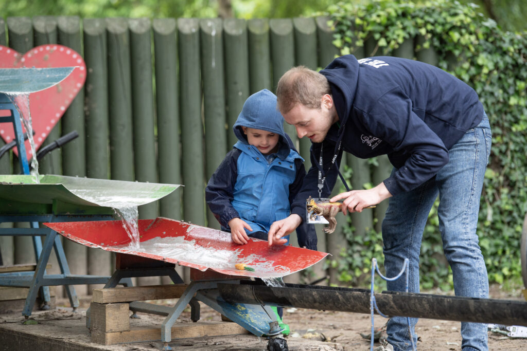 Male playworker and little boy at the water feature
