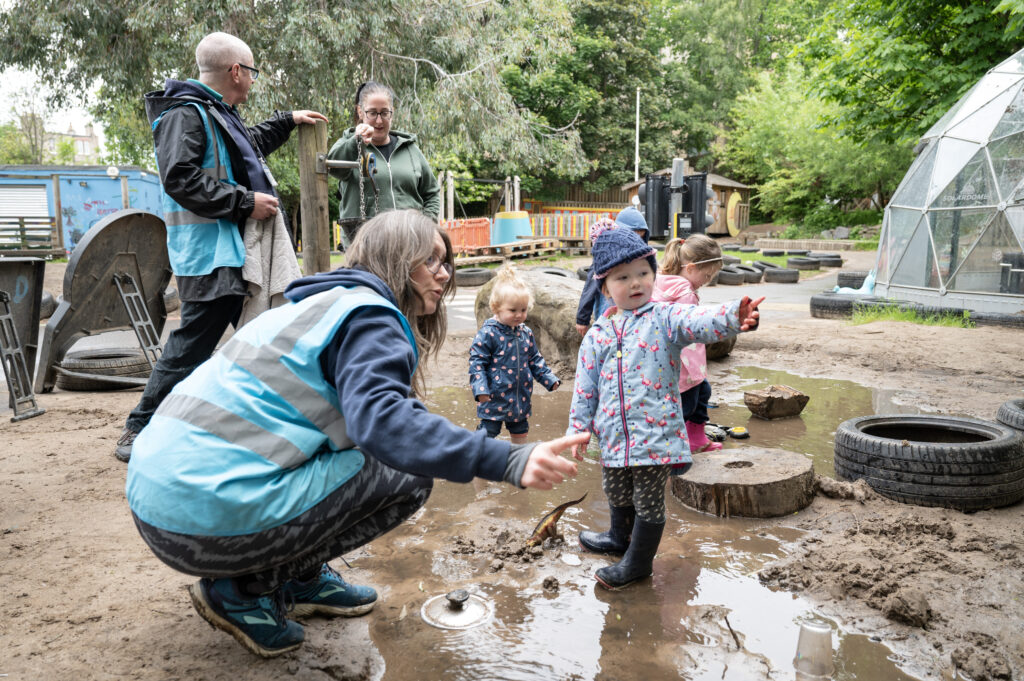 Yard staff and little girl playing in the water feature.