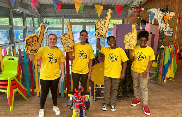 Group of teens fundraising for The Yard, wearing yellow t-shirts and holding foam fingers.