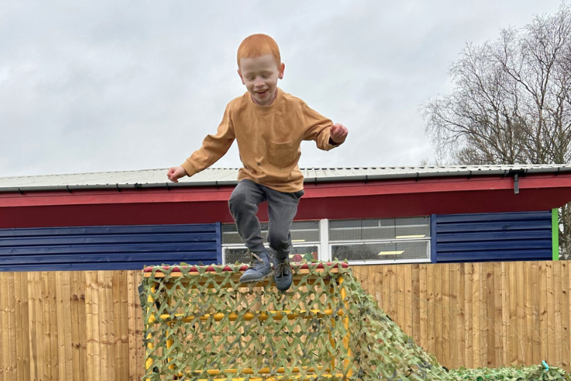 Little boy jumping off a climbing frame