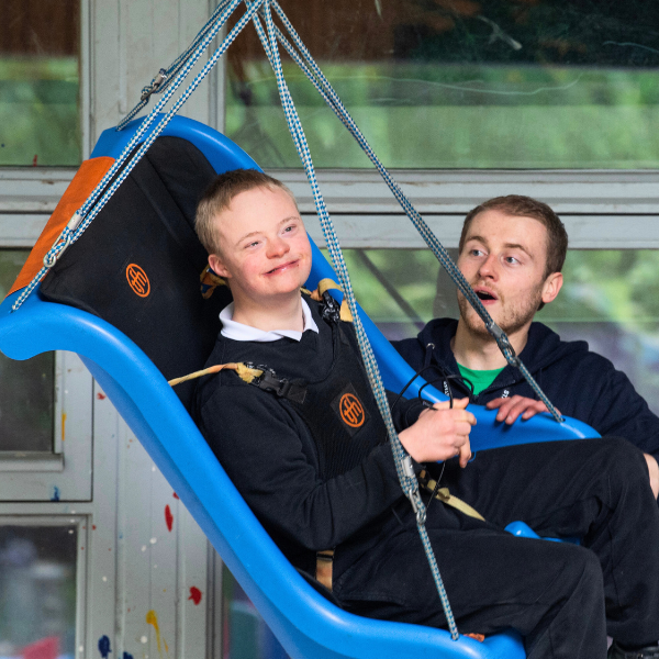 Staff member pushing a young boy on the sensory swing