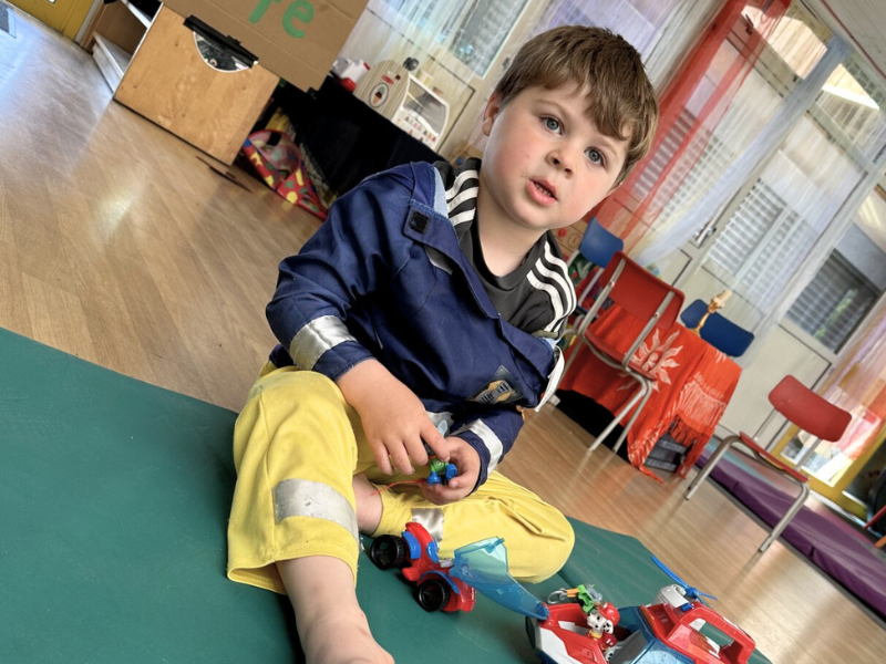 Young boy at The Yard, sitting on the floor playing with toy vehicles.