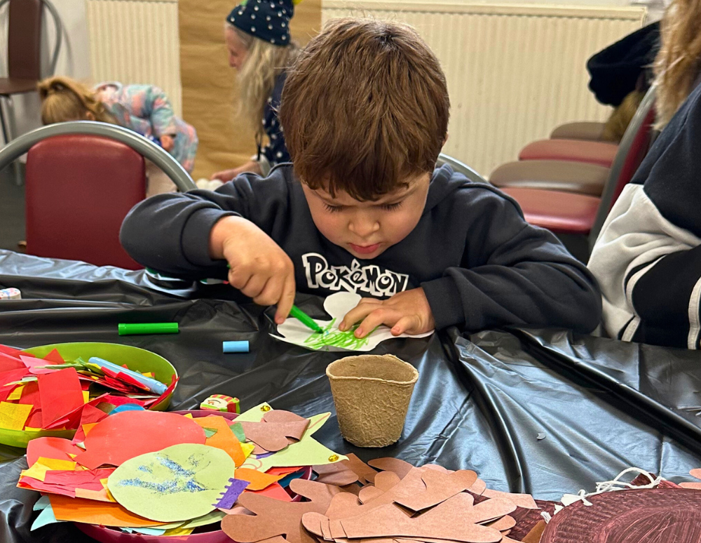 Young boy colouring in during arts and crafts.