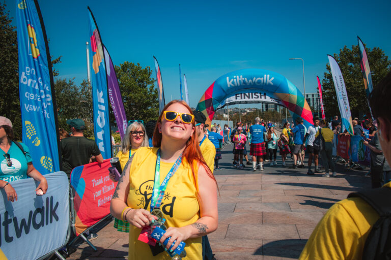 Woman smiling at the finish line with a Yard tshirt on