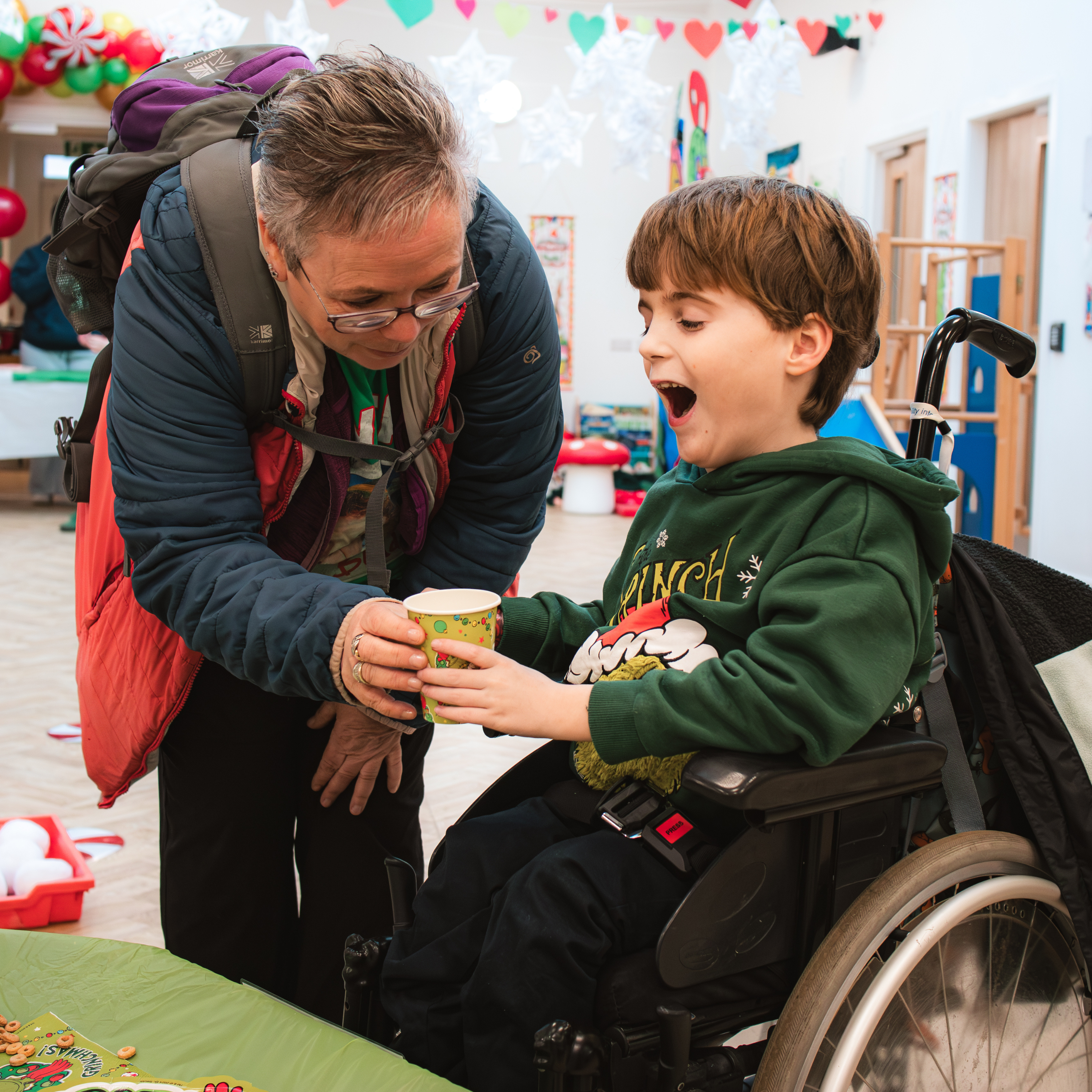 Little boy in wheelchair at the yard christmas party, smiling.