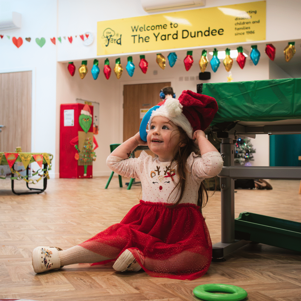 Little girl at the yard dundee, with santa hat, christmas outfit and smiling.