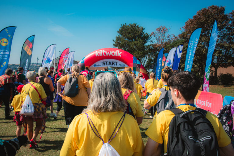 Lots of people in Yard tshirts walking over the start line at Kiltwalk